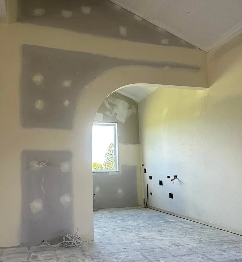 Interior room with plastered walls and an arched doorway finished with joint compound.