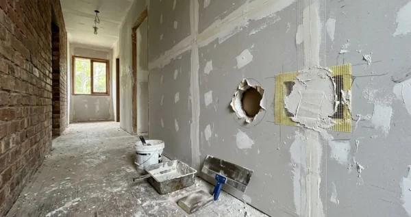 How to fix a hole in a plaster wall, with a doorknob hole, a mesh patch and plastering tools in a hallway